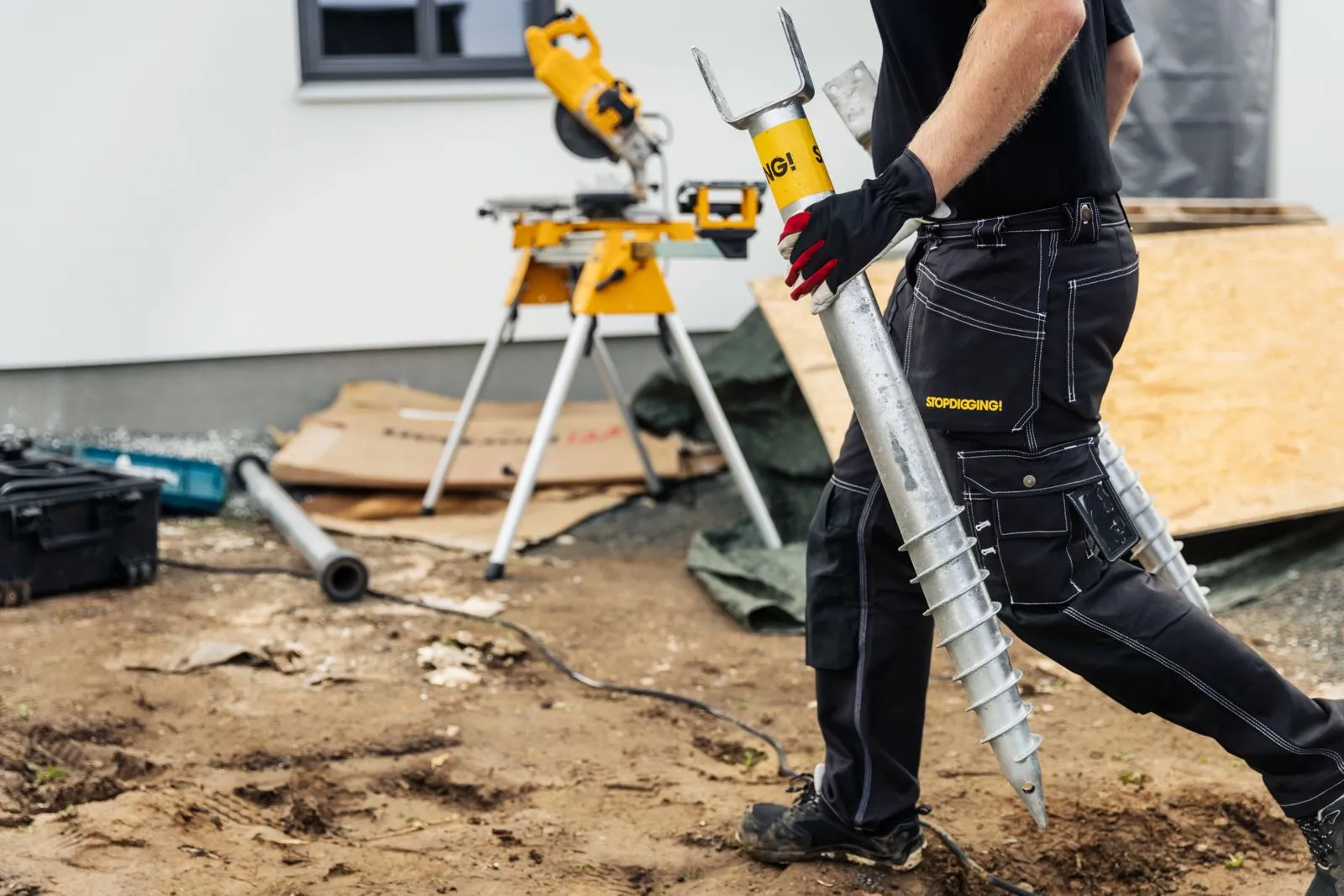 Crown Pavilions installer carrying galvanised ground screws on site